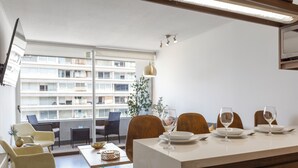 A modern dining area with a large window, a dining table, chairs, and a kitchen counter. - Modern Family Apartment in Las Condes (Las Condes)