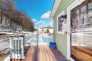 A wooden deck with a white railing, a green building with the number 18, and a clear sky. - Walk-to-town house, one-mile from Okemo Resort, a/c, w/d, wifi, yard, deck (Ludlow)