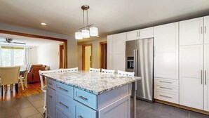 Una cocina moderna con encimera de granito, electrodomésticos de acero inoxidable y armarios blancos.