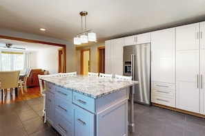 A modern kitchen with a granite countertop, stainless steel appliances, and white cabinetry. - Walk-to-town house, one-mile from Okemo Resort, a/c, w/d, wifi, yard, deck (Ludlow)