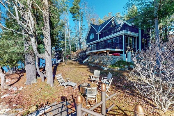 A large house with a porch, surrounded by trees and a clear sky.