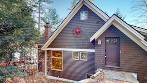 Ett modernt hus med en mörk fasad, en röd stjärndekoration på väggen och en skorsten.