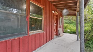 A red wooden building with large windows and a covered porch.