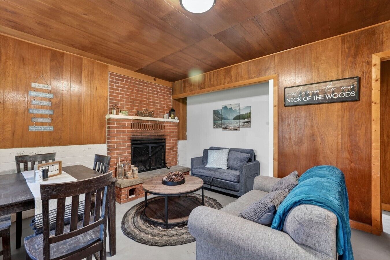 A cozy living room with a brick fireplace, a sofa, a coffee table, and a dining area with a table and chairs.