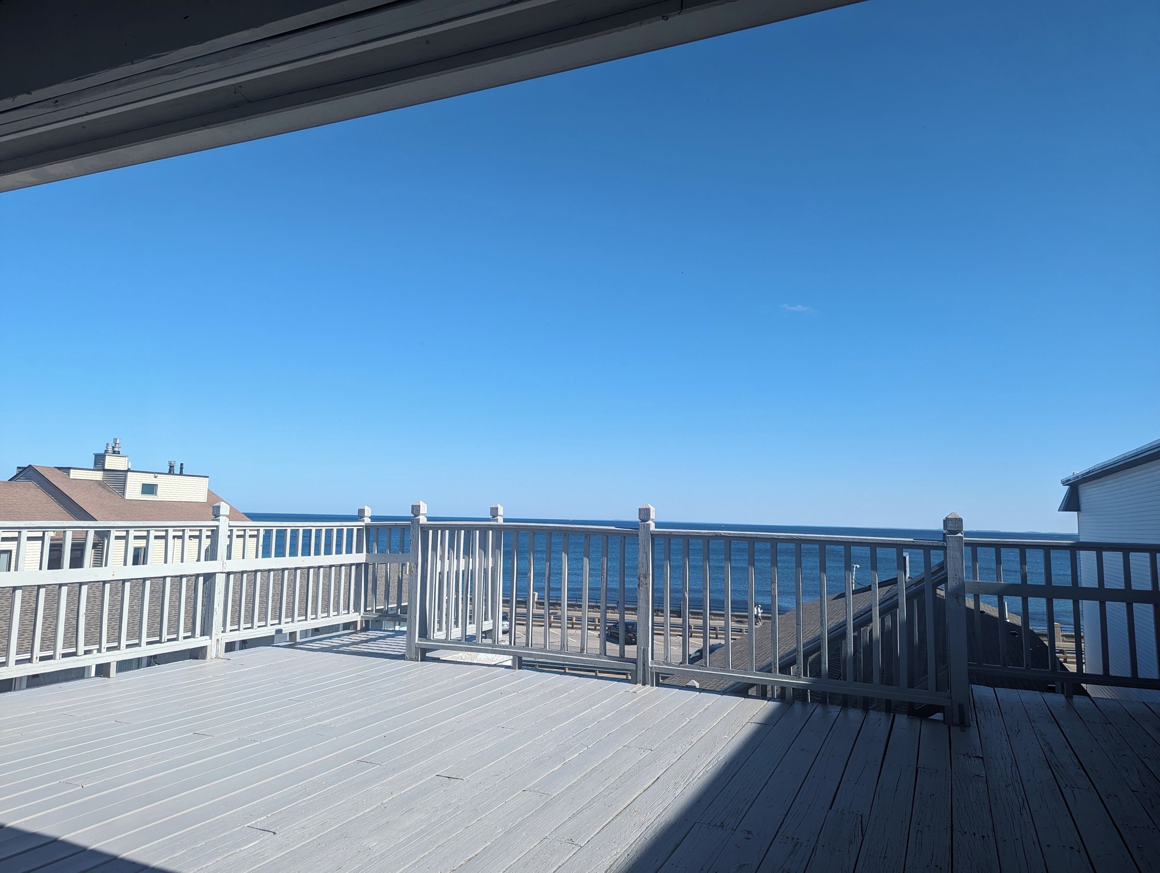 A wooden deck with a railing overlooking a beach.