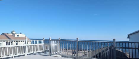 A wooden deck with a railing overlooking a beach.