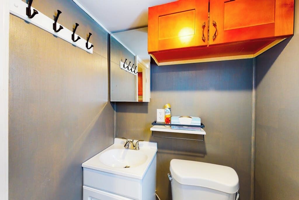 Ein Badezimmer mit Waschbecken, Toilette, Spiegel und Holzschränken.