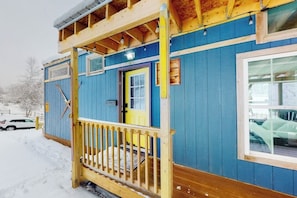A blue wooden cabin with a yellow door, a wooden porch, and a window. - Two cozy tiny homes with a private hot tub, large deck, grill, AC - dog friendly (Ludlow)