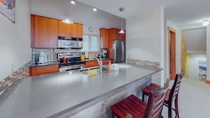 A modern kitchen with wooden cabinets, stainless steel appliances, and a central island with bar stools.