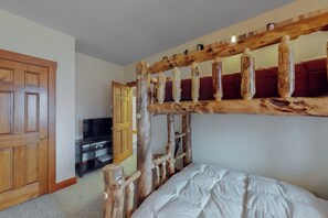 Una habitación con una cama de madera rústica, un televisor y una puerta.