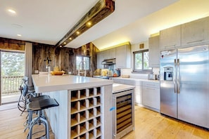 Eine moderne Küche mit einer zentralen Kochinsel, Edelstahlgeräten und einer Wand mit Holzverkleidung.