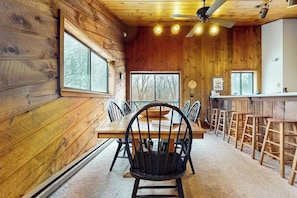 Ein Holzinterieur mit Esstisch, Stühlen und einer Bar.