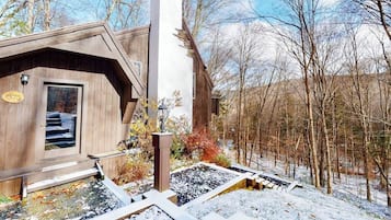 Une cabane en bois avec une cheminée, une porte avec une plaque portant un numéro et un paysage enneigé.