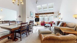 Ein geräumiges Wohnzimmer mit Essbereich, einer Sofagarnitur, einem Fernseher und einer Chandelier.