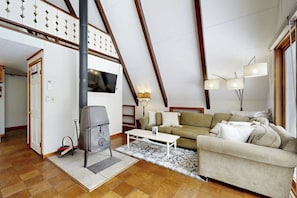 Ein Loft-Wohnzimmer mit Kamin, Sofa und Wand-Fernseher.