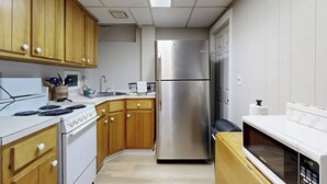 A kitchen with wooden cabinets, a stainless steel refrigerator, a stove, and a microwave. - Cozy duplex, first floor unit w/ kitchen, shared fire pit, lake access, wifi, TV (Ludlow)
