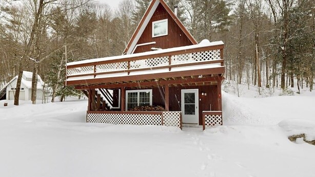 A wooden cabin with a balcony, surrounded by snow-covered trees. - Cozy duplex, first floor unit w/ kitchen, shared fire pit, lake access, wifi, TV (Ludlow)