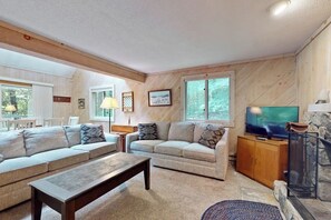 A living room with two sofas, a coffee table, a TV, and a stone fireplace.