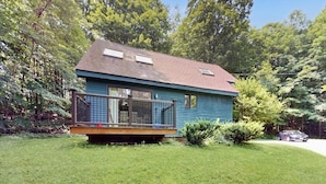 Eingeschossiges Haus mit Terrasse, umgeben von einem gepflegten Rasen und Bäumen.