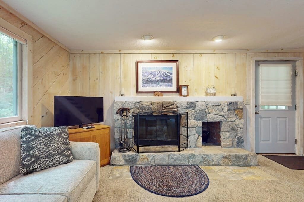 A living room with a stone fireplace, a television, and a couch.