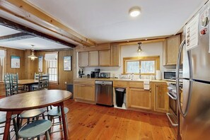 A kitchen with wooden cabinets, a dishwasher, a refrigerator, and a dining area with a table and chairs.