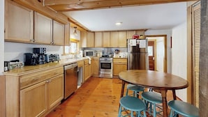 A kitchen with wooden cabinets, a central island with stools, a microwave, a stove, and a refrigerator.