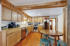 A kitchen with wooden cabinets, a central island with stools, a microwave, a stove, and a refrigerator.