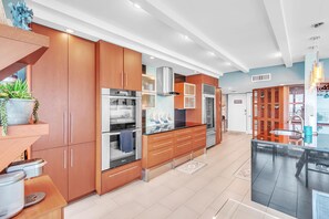 Eine moderne Küche mit Holzschränken, Edelstahlgeräten und einer schwarzen Arbeitsplatte.