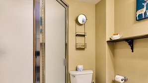 Ein Badezimmer mit Glasdusche, Toilette, Bidet, Handtuchhalter und Ablage für Toilettenartikel.