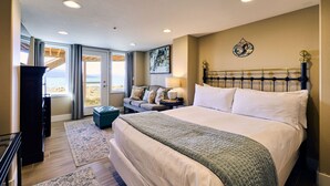 Ein Hotelzimmer mit einem großen Bett, einer Couch, einem Schreibtisch und Blick auf den Strand.