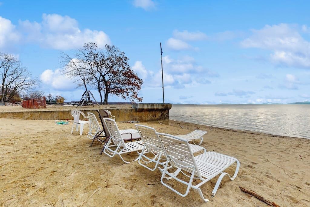 A beach with white lounge chairs and a concrete barrier.