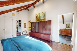 Ein Schlafzimmer mit Bett, Holzschrank und einem Bild an der Wand.