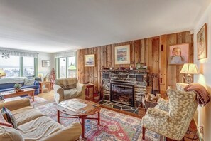 Ein gemütliches Wohnzimmer mit Kamin, Holzwänden und Blick ins Freie.