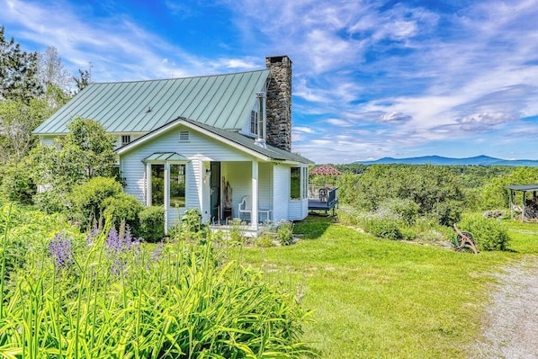 Ein Haus mit einem Steinkamin, einer Veranda und Blick auf die umliegende Landschaft.