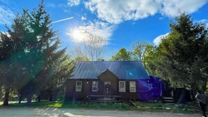 A rustic cabin with a metal roof, surrounded by trees, and a clear sky. - Dog-friendly getaway with mountain views, games, & deck - near skiing & trails (Mount Holly)