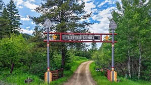 Uma estrada de terra que leva a um portão com uma placa que diz 'CLAUDE LEMHI'.
