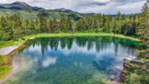 Um lago límpido rodeado por colinas verdes e árvores.