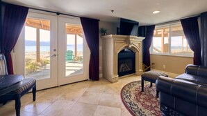 Una sala de estar con chimenea, vistas a la playa y un patio.