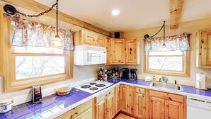 A kitchen with wooden cabinets, a white microwave, a stove, and a sink.