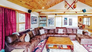 A cozy living room with a large brown leather sectional sofa, a wooden coffee table, and a fireplace.