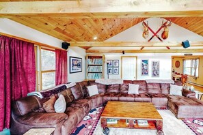 A cozy living room with a large brown leather sectional sofa, a wooden coffee table, and a fireplace. - Two-story, dog-friendly house (Wardsboro)