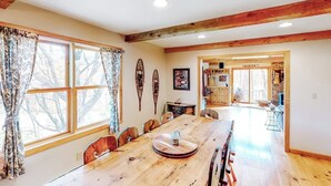 A dining area with a wooden table, chairs, and a window with curtains.