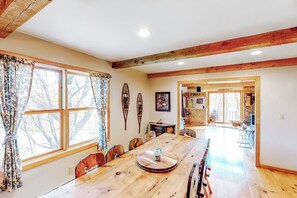 A dining area with a wooden table, chairs, and a window with curtains. - Two-story, dog-friendly house (Wardsboro)