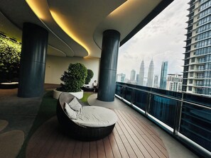 Ein moderner Balkon mit Korbstuhl, Blumentöpfen und Blick auf die Stadtlandschaft.