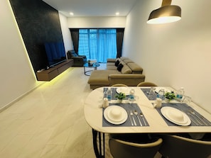 Ein modernes Wohnzimmer mit einer Couch, Fernseher und Essbereich, der zum Essen eingerichtet ist.