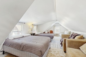 Une chambre avec deux lits, un canapé et une fenêtre.