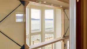 Ein Zimmer mit Blick auf einen Strand, Holzträgern und einem Deckenventilator.