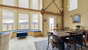Ein Zimmer mit großen Fenstern, einem Holzesstisch und einer Bank.
