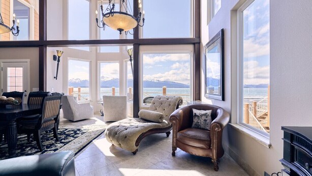 A spacious living room with a large window overlooking a scenic view, a chandelier, and a fireplace.