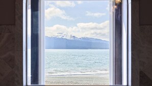 A bathroom with a window overlooking a lake and mountains.